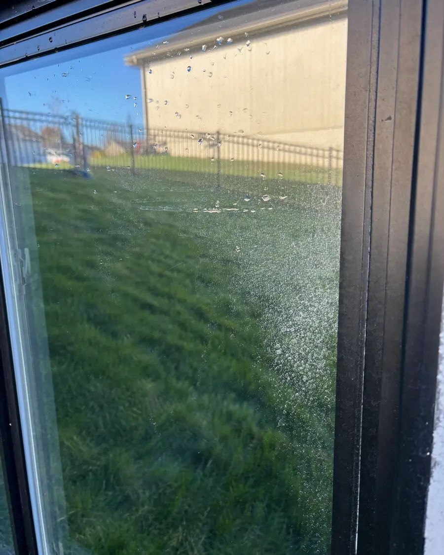 Window covered in hard water spots before cleaning