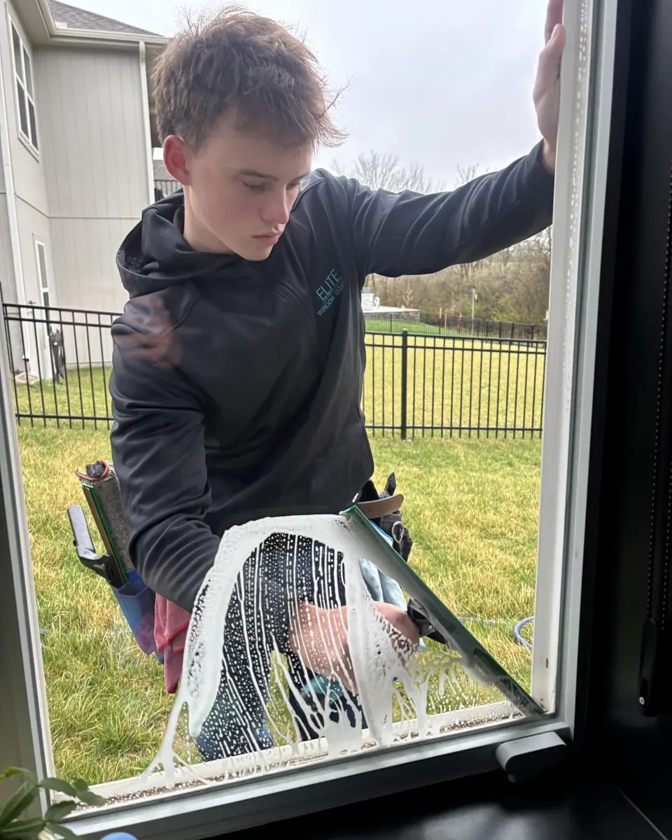 Crew member squeegeeing a soapy patio door