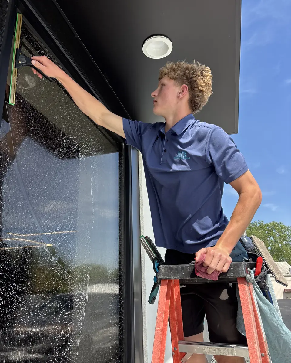 Chandler squeegeeing a large window from a ladder
